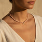 Collar CGK Style de cuentas rosa pastel y detalles dorados con un dije de corazón puesto en el cuello de una mujer